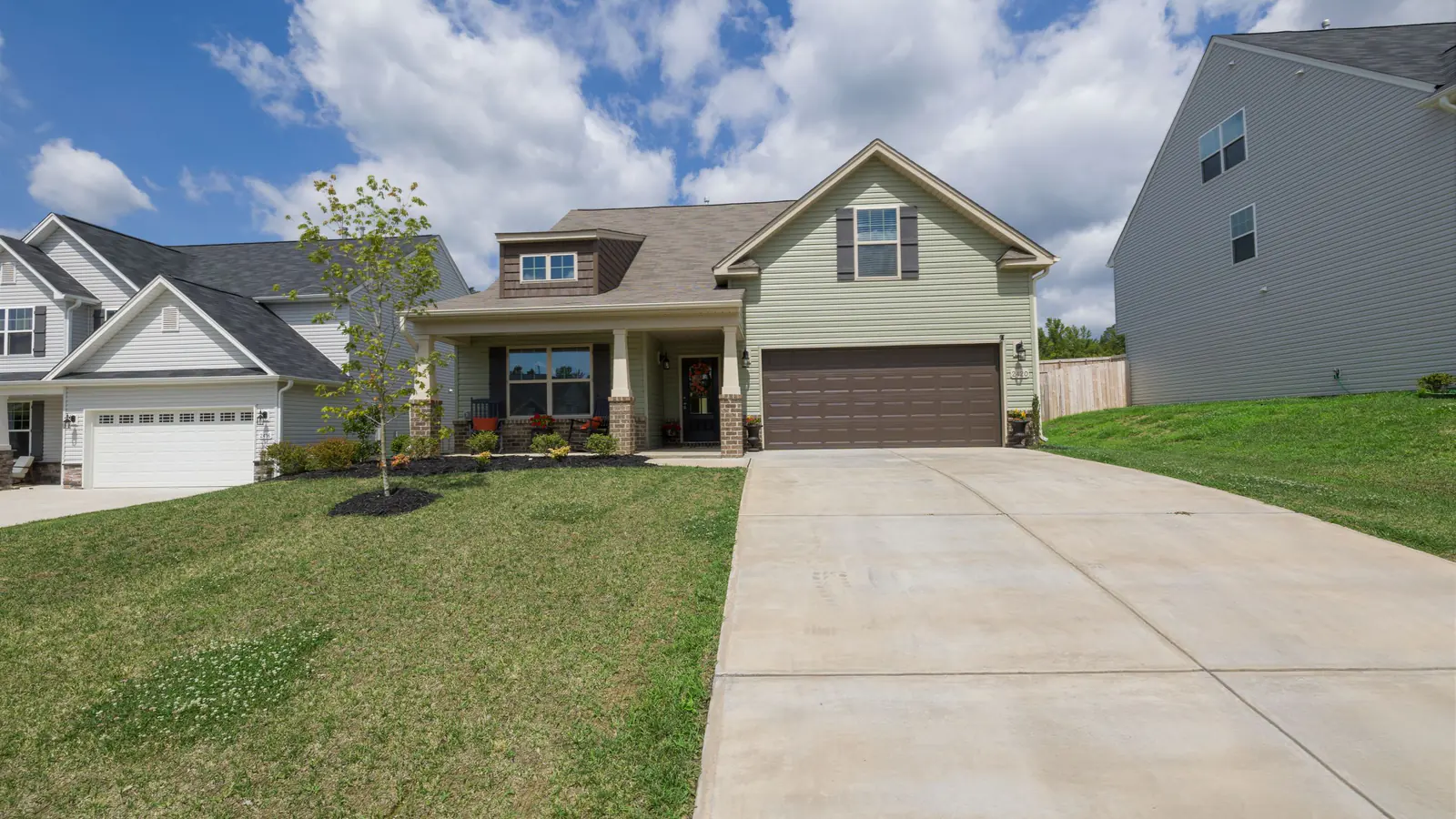 A modern suburban detached house with an attached garage at the end of a concrete driveway.